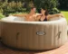 Мъж и жена се къпят в бежово надуваемо джакузи Intex PureSpa на тераса с червени плочки в градина