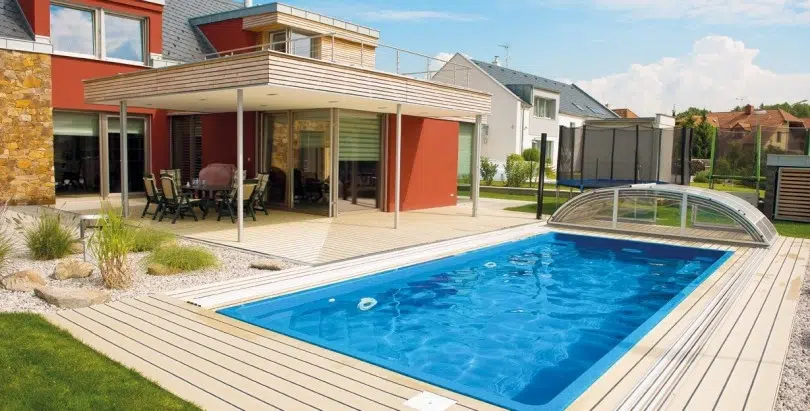 Einbaupool mit Teleskopüberdachung neben einem modernen Haus