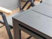 Ecke der Platte des Tisches Essence neben einem klappbaren Sessel mit Teak-Armlehnen
