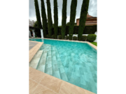 Pool mit Treppe und armierter Poolfolie Cefil Keramik Sunlight zwischen hohen Zypressen