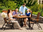 Friends around a Flamingo garden table on a terrace with stone paving