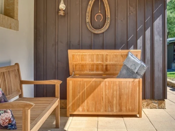 Gentle teak cushion box with cushions inside on a veranda next to a wooden bench