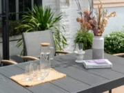 Tisch Essence mit Kanne, Gläsern und Vase mit Trockenblumen auf einer Terrasse