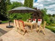 Rechteckiger Gartentisch Vegas aus Teak mit Stühlen und großem Sonnenschirm auf einer Terrasse