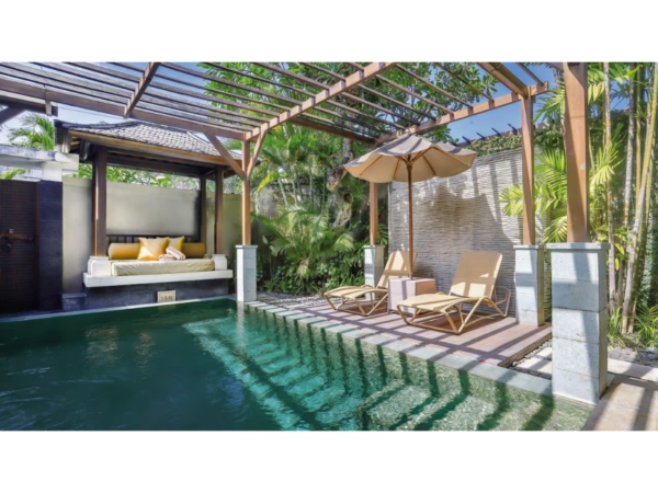 Piscină cu apă verde închis lângă un foișor tropical și șezlonguri