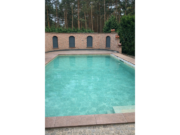 Pool mit armierter Poolfolie Cefil Victoria Ocra neben einer Backsteinmauer mit Bögen