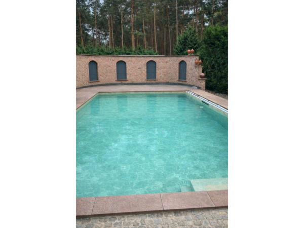 Pool mit armierter Poolfolie Cefil Victoria Ocra neben einer Backsteinmauer mit Bögen