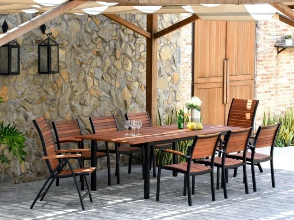 Ausziehtisch Flamingo mit Sesseln auf einer Terrasse mit Sonnenschutz und Steinmauer