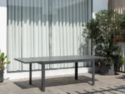Ausgezogener Tisch Essence auf einer Terrasse vor einem großen Fenster mit hellen Vorhängen