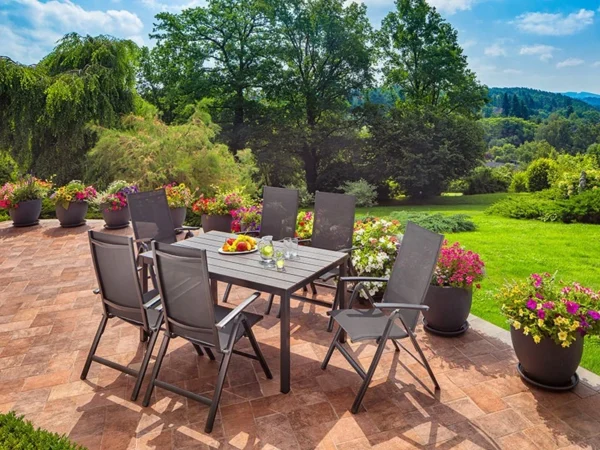 Klappbare Sessel Alegria um einen Tisch auf einer Terrasse mit Blumen und Garten