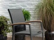 Scaun de grădină Essence în fața unui zid de cărămidă albă, printre ghivece cu plante