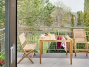 Scaun de balcon Ambra pe un balcon, iar al doilea scaun este pliat lângă masă