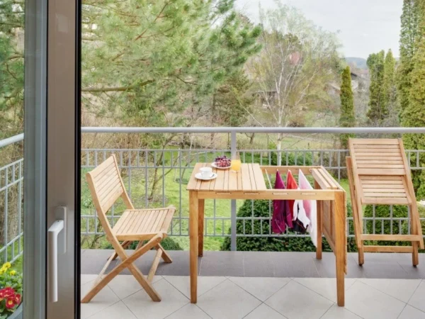 Scaun de balcon Ambra pe un balcon, iar al doilea scaun este pliat lângă masă