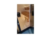 Сауна Iconix Panorama L с отворена стъклена врата и поглед към пода, пейката и печката