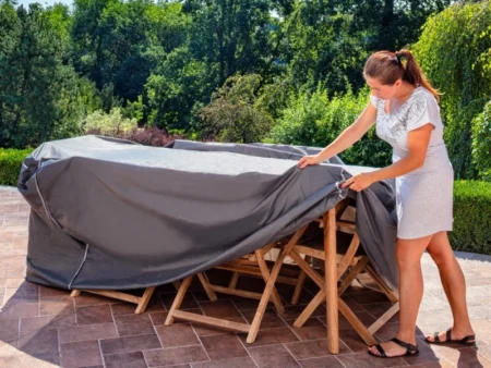 Husă de protecție pentru mobilier de grădină, așezată peste o masă cu scaune pe terasă