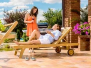Женщина отдыхает с бокалом вина на лежаке из тика Gentle на террасе