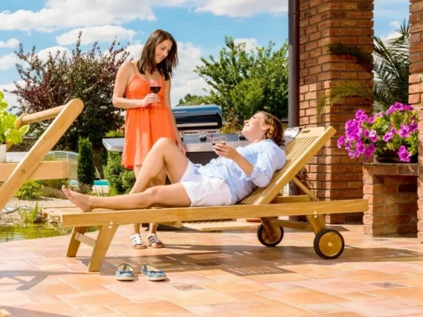 Женщина отдыхает с бокалом вина на лежаке из тика Gentle на террасе